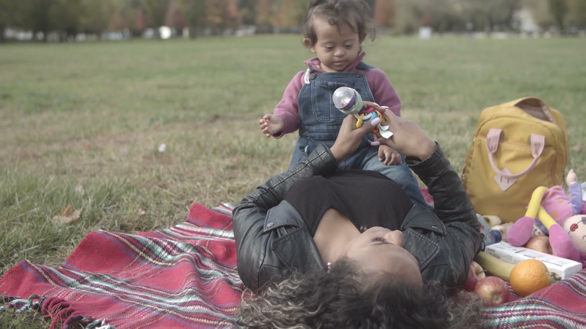A mother playing with her young child in a leafy park
